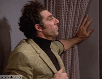 A Man In A Suit And Turtleneck Is Looking Out A Window With A Gif-Finder.com Watermark In The Corner GIF
