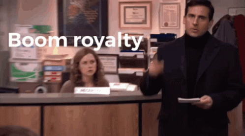 A Man In A Suit And Turtleneck Stands In Front Of A Woman At A Desk With The Words Boom Royalty Above Him GIF