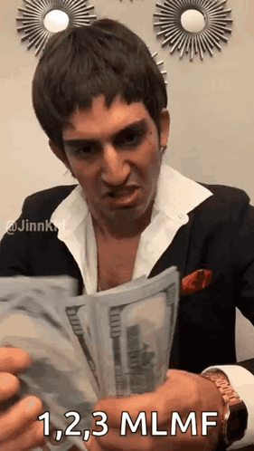 A Man In A Suit And White Shirt Is Holding A Bunch Of Money And Says `` 1,2,3 Mlnf '' . GIF