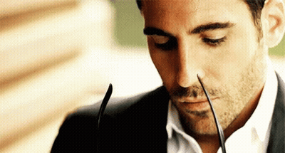 A Man In A Suit And White Shirt Is Holding A Pair Of Glasses In His Mouth . GIF