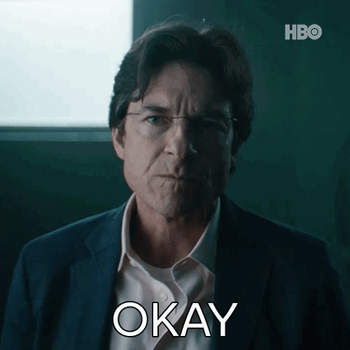 A Man In A Suit And White Shirt Is Making An Okay Gesture GIF