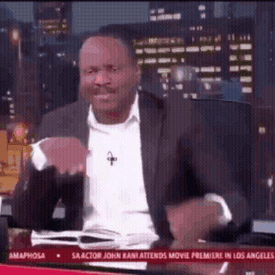 A Man In A Suit And White Shirt Is Sitting In Front Of A Tv Screen That Says Amaphorsa GIF