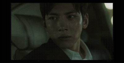 A Man In A Suit And White Shirt Is Sitting In The Back Seat Of A Car And Looking At The Camera . GIF