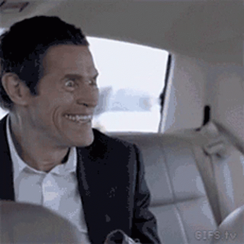 A Man In A Suit And White Shirt Is Sitting In The Back Seat Of A Car And Smiling . GIF