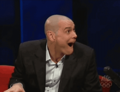 A Man In A Suit And White Shirt Is Smiling In Front Of A Nbc Logo GIF