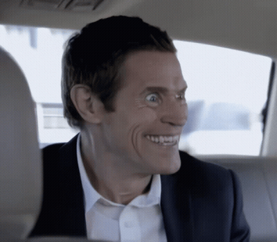 A Man In A Suit And White Shirt Is Smiling In The Back Of A Car GIF