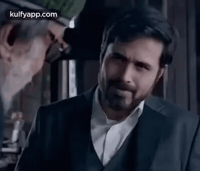 A Man In A Suit And White Shirt Is Standing In Front Of A Mirror . GIF
