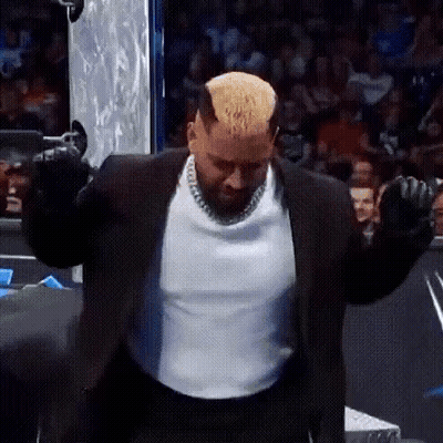 A Man In A Suit And White Shirt Is Standing With His Arms Outstretched In Front Of A Crowd . GIF