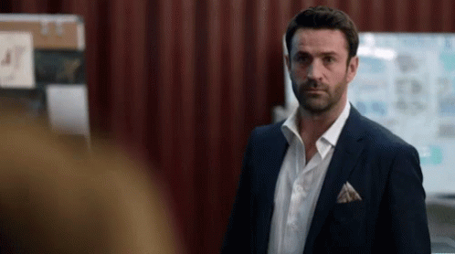 A Man In A Suit And White Shirt Stands In Front Of A White Board With The Number 47 On It GIF
