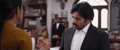 a man in a suit and white shirt talks to a woman