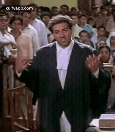 A Man In A Suit And Wig Is Giving A Speech In Front Of A Crowd Of People . GIF