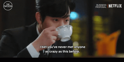 A Man In A Suit Drinking From A White Cup With A Netflix Logo In The Background GIF