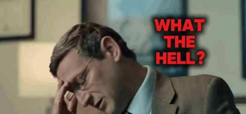 A Man In A Suit Has His Hand On His Forehead In Front Of A Sign That Says " What The Hell " GIF
