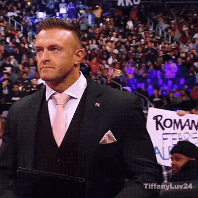 A Man In A Suit Holding A Sign That Says Roman Fears All GIF