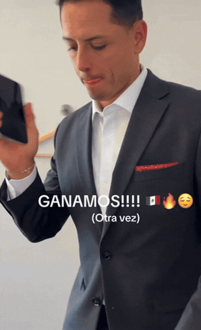 A Man In A Suit Holds A Cell Phone And Says Ganamos GIF