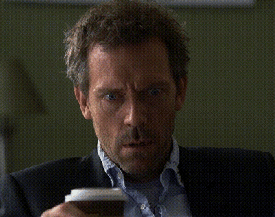 A Man In A Suit Holds A Cup Of Coffee In His Hand GIF