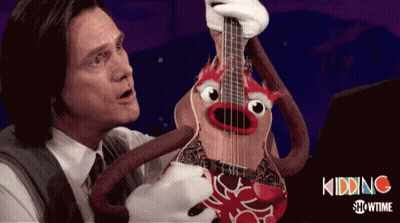 A Man In A Suit Holds A Guitar With A Crab Face On It GIF