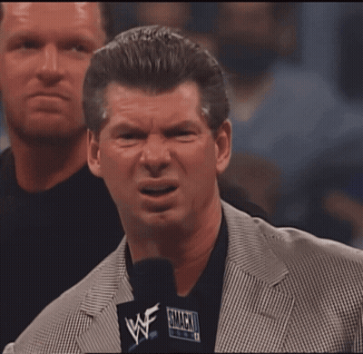 A Man In A Suit Holds A Microphone That Says Wwe On It GIF