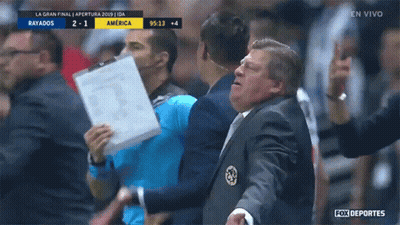 A Man In A Suit Holds A Piece Of Paper In Front Of A Fox Deportes Sign GIF