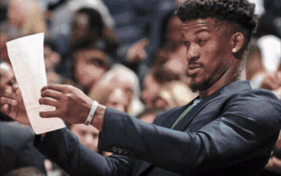 A Man In A Suit Holds A Piece Of Paper In His Hand GIF