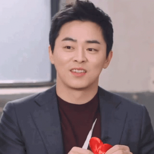 A Man In A Suit Holds A Red Heart In His Hands GIF