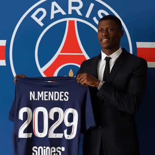 A Man In A Suit Holds Up A Shirt That Says 2029 GIF