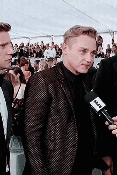 A Man In A Suit Is Being Interviewed By A Man Holding A Microphone With A Label That Says Tnt GIF