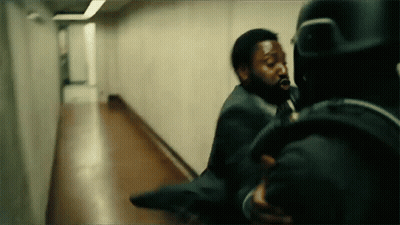 A Man In A Suit Is Being Thrown By Another Man In A Hallway . GIF