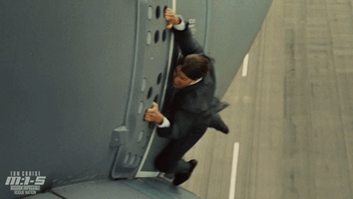 A Man In A Suit Is Climbing Up A Wall In A Scene From The Movie Mission Impossible Rogue Nation GIF
