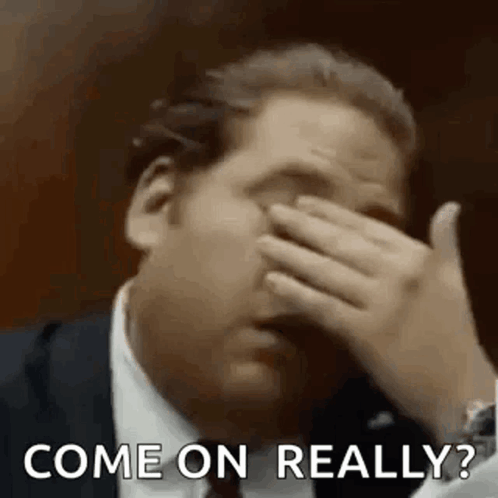 A Man In A Suit Is Covering His Face With His Hand And The Words `` Come On Really '' . GIF