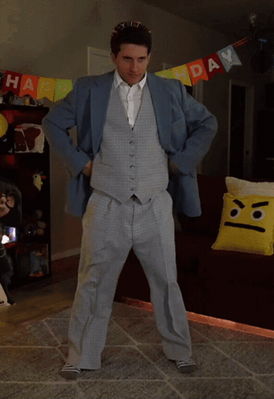 A Man In A Suit Is Dancing In Front Of A Birthday Banner GIF