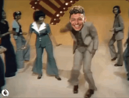 A Man In A Suit Is Dancing In Front Of A Crowd Of People GIF
