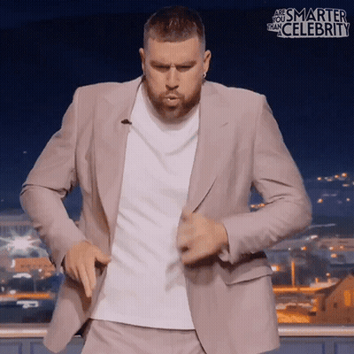 A Man In A Suit Is Dancing In Front Of A Sign That Says Smarter Than Celebrity GIF