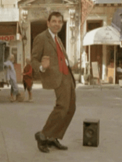 A Man In A Suit Is Dancing On A Sidewalk In Front Of A Store That Says Mop GIF