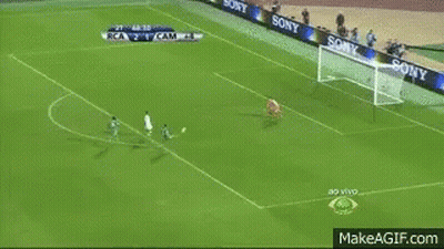 A Man In A Suit Is Dancing On A Soccer Field . GIF