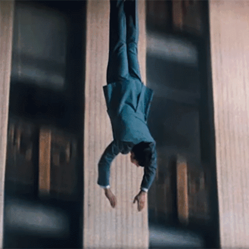 A Man In A Suit Is Doing A Handstand In The Air GIF