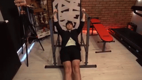 A Man In A Suit Is Doing Pull Ups On A Machine In A Gym . GIF
