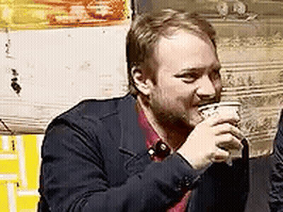 A Man In A Suit Is Drinking A Cup Of Coffee . GIF