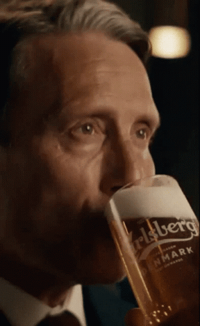 A Man In A Suit Is Drinking From A Carlsberg Glass GIF