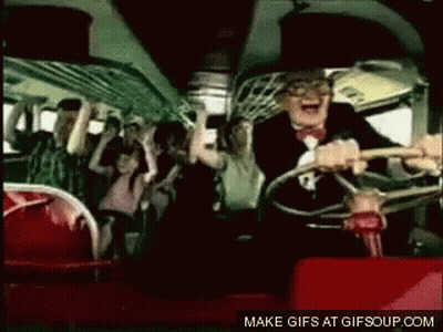 A Man In A Suit Is Driving A Bus With A Crowd Of People On It . GIF