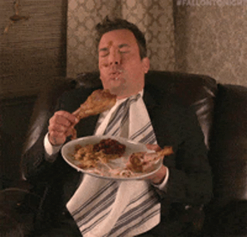 A Man In A Suit Is Eating A Plate Of Food GIF