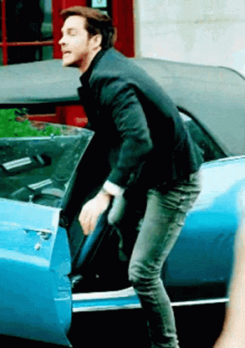 A Man In A Suit Is Getting Out Of A Blue Car GIF