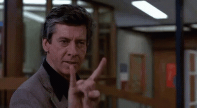 A Man In A Suit Is Giving The Middle Finger In A Room . GIF
