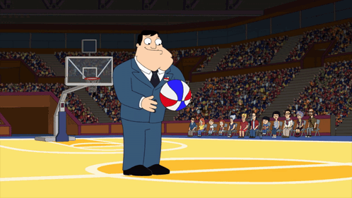A Man In A Suit Is Holding A Basketball In Front Of A Crowd GIF