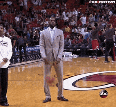 A Man In A Suit Is Holding A Basketball On A Basketball Court With A Abc Logo In The Background GIF