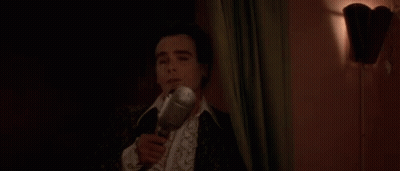 A Man In A Suit Is Holding A Bottle Of Wine In His Hand . GIF