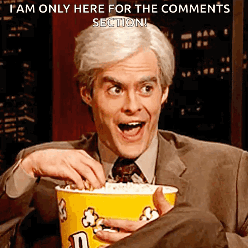 A Man In A Suit Is Holding A Bucket Of M & M 'S Popcorn GIF