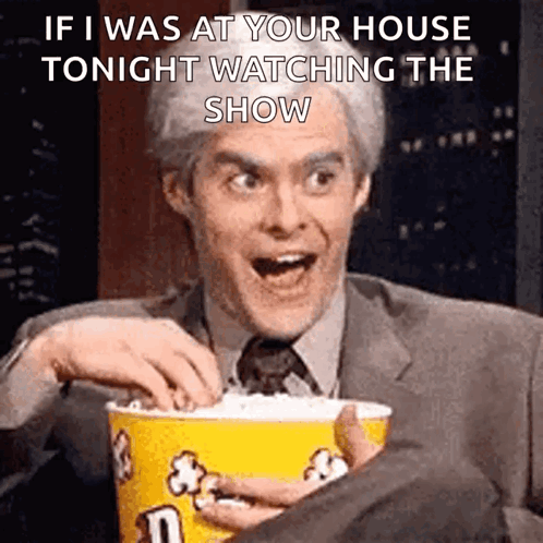 A Man In A Suit Is Holding A Bucket Of Popcorn GIF