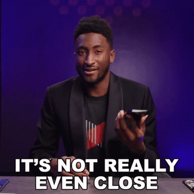 A Man In A Suit Is Holding A Cell Phone With The Words It 'S Not Really Even Close Below Him GIF