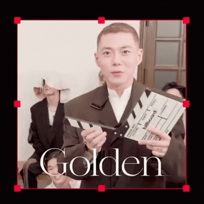 A Man In A Suit Is Holding A Clapper Board That Says Billboard On It GIF